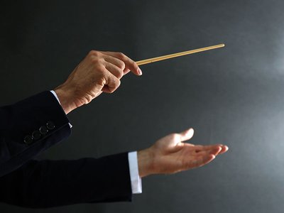 Music conductor hands with baton on black background